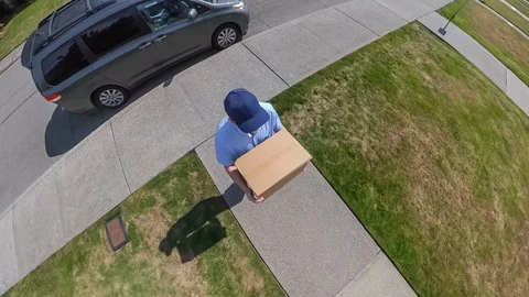 Mail man delivers a package to a colonial style home Vídeos de archivo 116556003