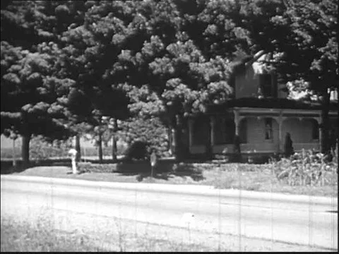 A mailman in a car is given a parcel by a local woman which he weighs and posts Stock Footage 75303318