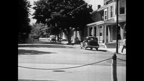 A mailman in a car is given a parcel by a local woman which he weighs and posts Stock Footage 83159637