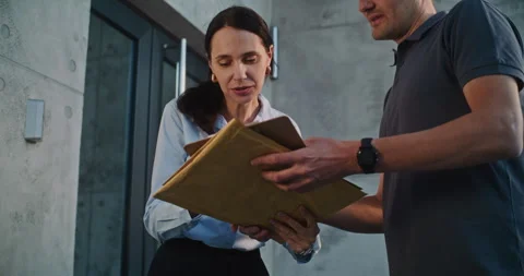 Mailman Delivering Padded Envelope for Recipient in Modern Office, Getting Stock Footage 312383397