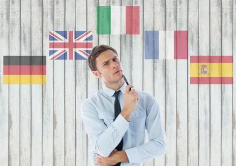 Main language flags around young businessman thinking. Wood background Foto stock