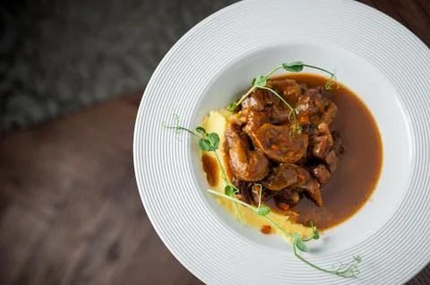 The main meat dish on a large deep plate. Restaurant Stock Photos