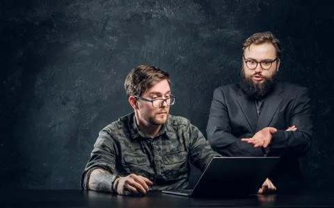 The main programmer of the company indicates errors to his subordinate in office Stock Photos