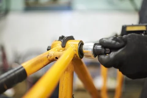 Maintenance of a bicycle: person disassembling an orange bike at his repair.. Stock Photos