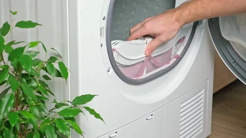 Maintenance dryer after drying cycle. Drying machine Man takes out dirty filter Stock Footage 220886056