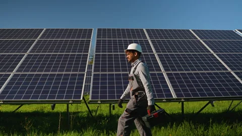 Maintenance engineer carrying toolbox while walking near solar panels Video stock 314404047
