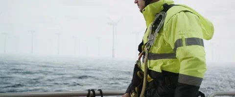 Maintenance engineer standing on a service vessel approaching offshore wind farm Stock Footage 245351356