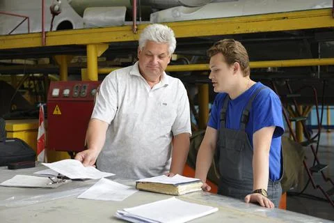 At the maintenance hall. Engineer and worker standing at the working place an Stock Photos