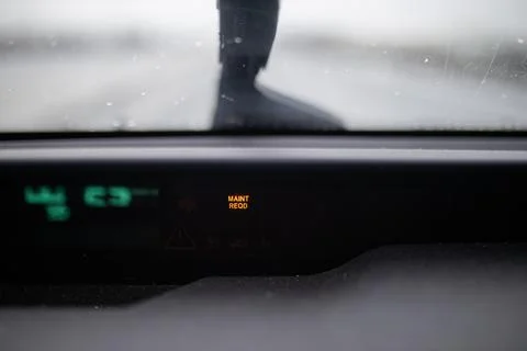 Maintenance required light shining on dashboard under a wet windshield Stock Photos