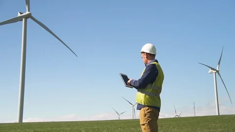 Maintenance standing near wind mill and using tablet Stock Footage 113998743