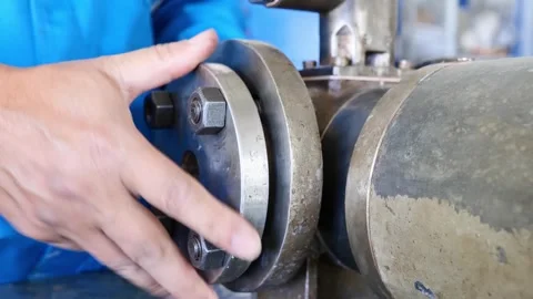 Maintenance technician tightening nuts on pipe flanges during machine assembly i Stock Footage 304068427