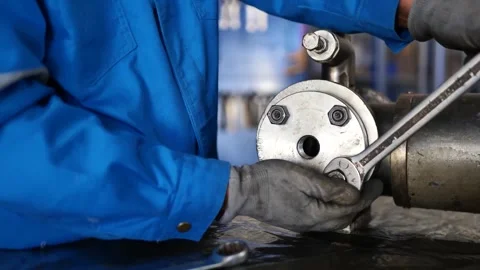 Maintenance technician using a wrench to tighten flange nuts on industrial machi Stock Footage 304069167