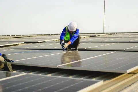 Maintenance technicians installing solar panels at solar cell farm Stock Photos