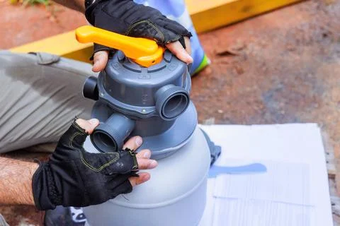 Maintenance worker assembles sand filter system tank, a equipment used to clean Stock Photos