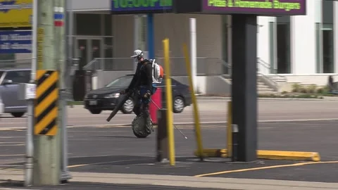 Maintenance worker rides unicycle cleaning parking lot with leaf blower Video stock 152605239