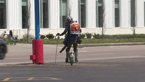 Maintenance worker rides unicycle cleaning parking lot with leaf blower Vidéo 152605699