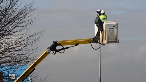 Maintenance worker using cherry picker to replace bulb in streelight uk Stock Footage 90374206