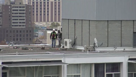 Maintenance Workers Working on Top of a High-Rise Building Stock Footage 69759277