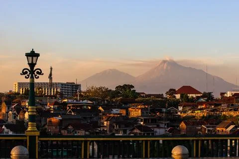 Majestic Active Mount Merapi Volcano with Cityscape View at Sunset, Residen.. Stockfoto's