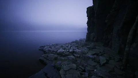 Majestic basalt cliffs extend into tranquil waters under soft foggy sky Stock Footage 340349284