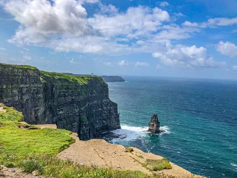 Majestic cliffs rise dramatically above the ocean, with vibrant green grass.. Stock Photos