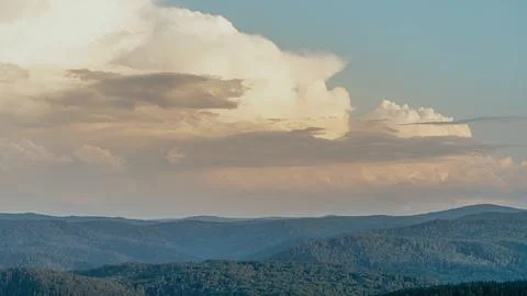 Majestic cloud formations hovering over rolling green hills at sunset in a Stock Photos