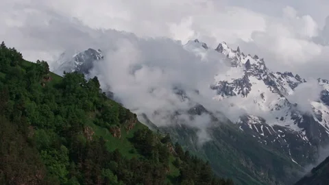 Majestic clouds drifting gracefully over towering mountain peaks Video stock 289655634