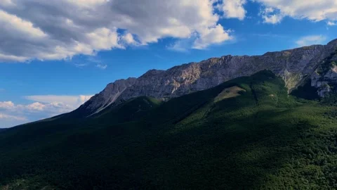 Majestic clouds gracefully drifting over a lush mountain range Video stock 282873516