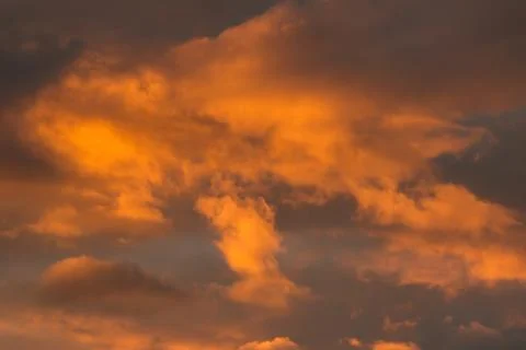 Majestic dramatic clouds illuminated by orange golden hour sunset light over Stock Photos