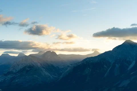 Majestic mountain range basked in soft, ethereal sunlight during sunrise. Stock Photos