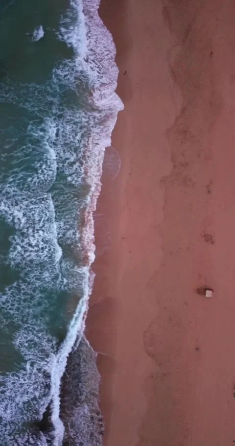 Majestic top-down aerial view of turquoise ocean waves gently rolling onto a Stock Footage 344820679