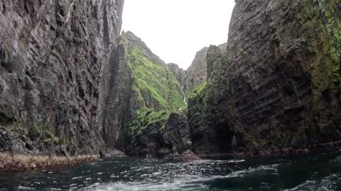 Majestic vertical volcanic cliffs and mountain cascade surrounded by ocean water Vidéo 339318708