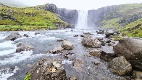 Majestic waterfall cascading down basalt columns and flowing into a rocky river Stock Footage 346325037