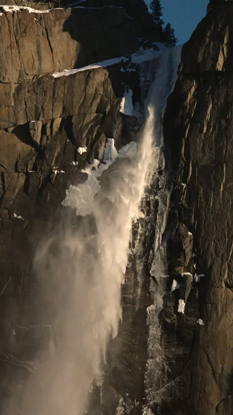 Majestic Waterfall Cascading Down Granite Cliff Face in Winter Mountains Видео 342944533