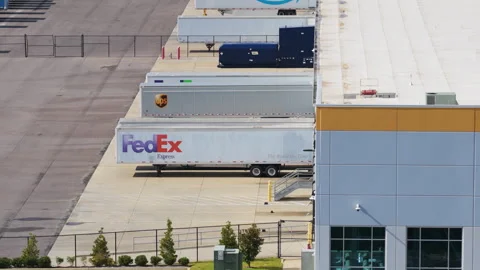 Major carriers line Amazon warehouse in telephoto aerial logistics scene Stock Footage 329503243