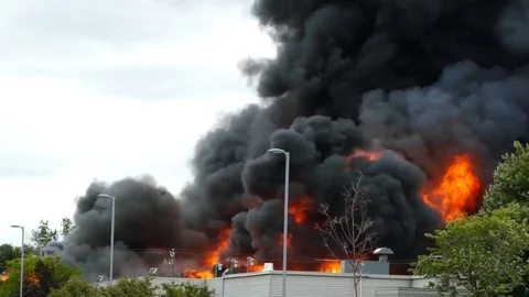 Major smoke billowing up from a building fire with heavy flames at daytime Stock Footage