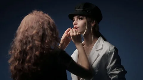A make-up artist and a stylist work with a model in a black hat Video stock 81064402