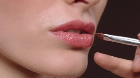 Make-up artist apply red lipstick with brush in hand. Young woman model lips and Stock Footage 147605630