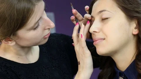 Make-up artist applying bright base color eyeshadow on model's eye Stock Footage 70192353