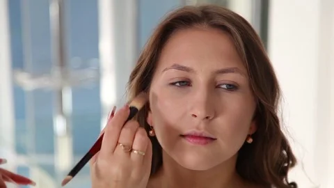 Make-up artist applying bright base color eyeshadow on model's eye , close up Stock Footage 76544314