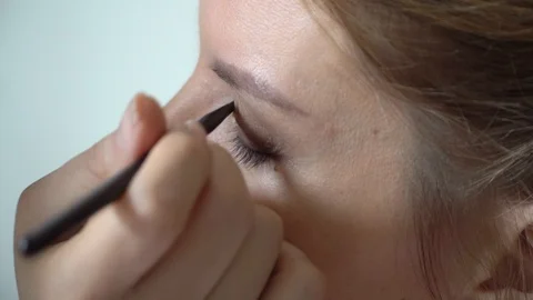Make-up artist applying bright base color eyeshadow on model's eye Stock Footage 86283408