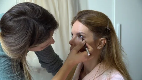 Make-up artist applying bright base color eyeshadow on model's eye Stock Footage 86283419