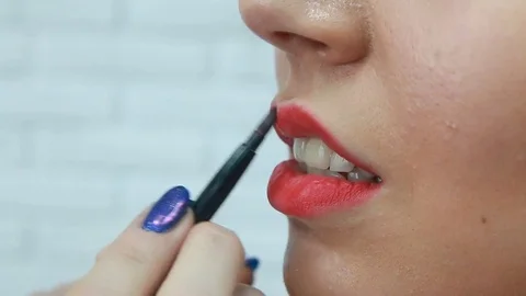 Make-up artist applying bright lipstick to model's lips Stock Footage 81535366
