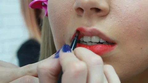 Make-up artist applying bright lipstick to model's lips Stock Footage 81535372