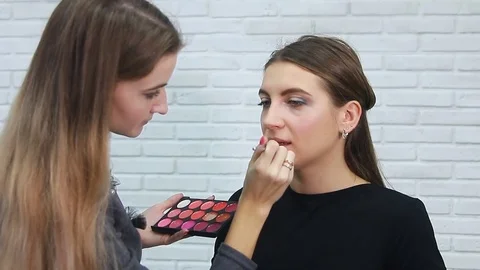 Make-up artist applying bright lipstick to model's lips Stock Footage 81935809
