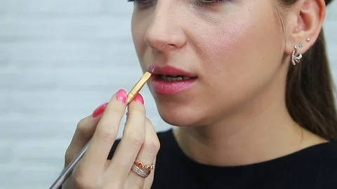 Make-up artist applying bright lipstick to model's lips Stock Footage 81935878