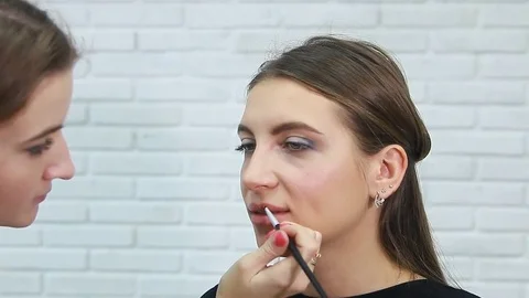 Make-up artist applying bright lipstick to model's lips Stock Footage 81935912