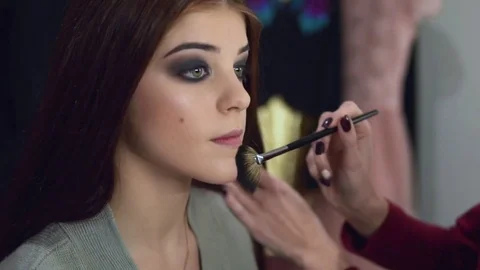 Make-up artist applying face powder on the model's face using special brush Stock Footage 71812301