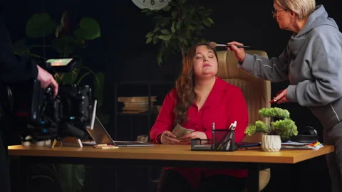 Make-up artist applying face powder on female model during business video shoot Stock Footage 329770613