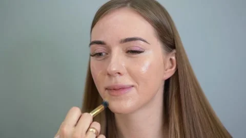 Make-up artist applying foundation on the face of a woman by brush. Salon Stockbeeldmateriaal 154964879